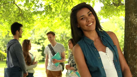 Happy-student-posing-and-friends-speaking-behind-her-