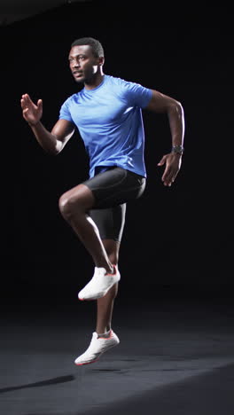 Vertikales-Video:-Afroamerikanischer-Männlicher-Athlet-Trägt-Blaues-Hemd,-Schwarzer-Hintergrund