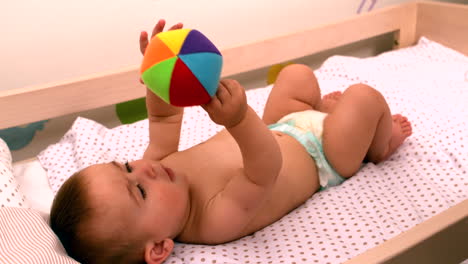 Baby-lying-in-crib-holding-toy