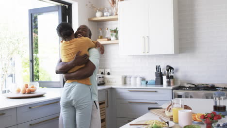 Una-Pareja-Afroamericana-Comparte-Un-Cálido-Abrazo,-Abrazándose-En-Una-Cocina.