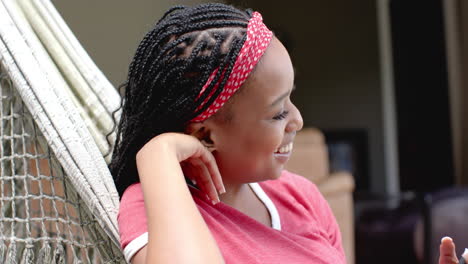 African-American-young-woman-relaxing-in-hammock,-smiling