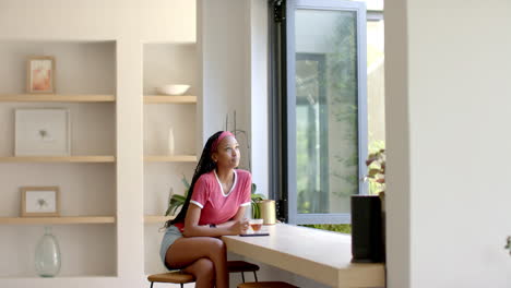 African-American-young-woman-sitting,-looking-at-laptop