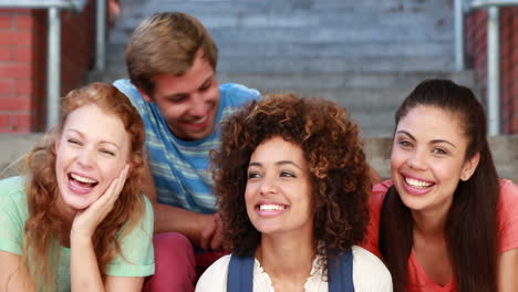 Happy-students-sitting-on-steps-smiling-at-camera