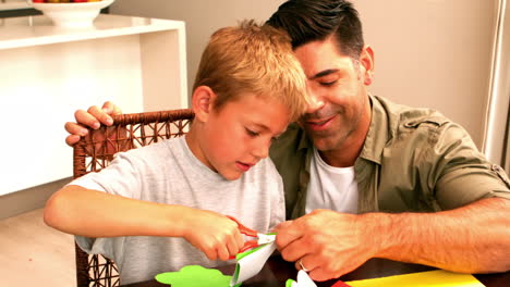 Padre-E-Hijo-Haciendo-Formas-De-Papel-Juntos-En-La-Mesa