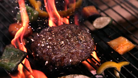 Burger-being-seasoned-on-flaming-barbecue