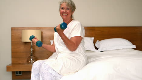 Senior-woman-lifting-dumbbells-in-bedroom