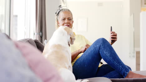 A-senior-African-American-woman-holding-smartphone,-sitting-with-dog
