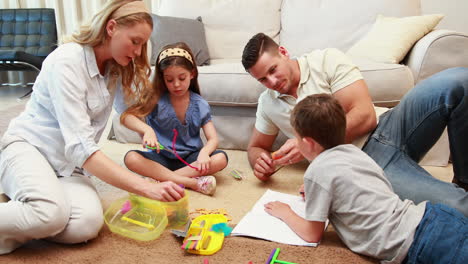Young-siblings-doing-arts-and-crafts-on-the-rug-with-parents