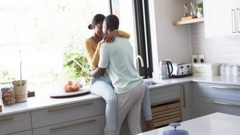 A-diverse-couple-shares-an-affectionate-moment-in-a-modern-kitchen,-hugging