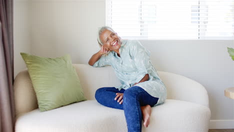 African-American-senior-woman-sitting-on-couch,-smiling-at-camera