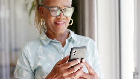 African-American-senior-woman-wearing-glasses,-looking-at-smartphone
