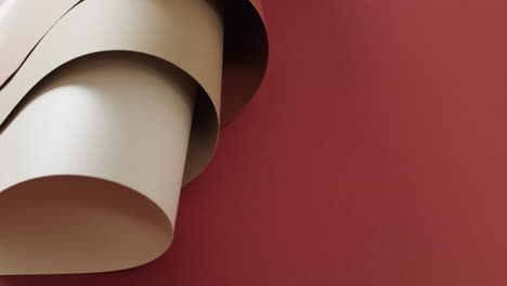 Close-up-of-brown-rolled-pieces-of-paper-on-red-background-with-copy-space-in-slow-motion