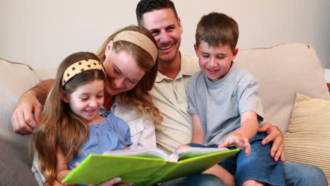 Happy-young-family-sitting-on-sofa-looking-at-photo-album