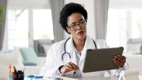 African-American-female-doctor-in-a-white-lab-coat-reviews-a-tablet-on-video-call-consultation
