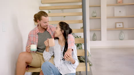 A-diverse-couple-enjoys-a-warm-beverage-on-the-stairs-at-home
