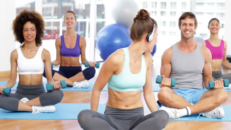 Fitness-class-sitting-together-and-lifting-dumbbells