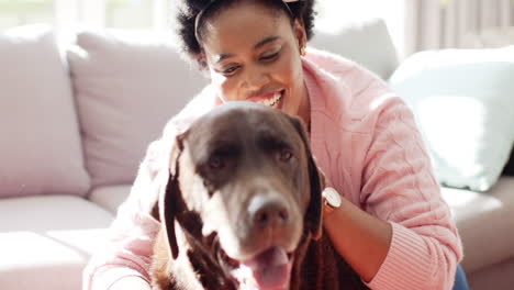 African-American-woman-cuddles-with-a-brown-Labrador-dog-on-a-sofa-at-home