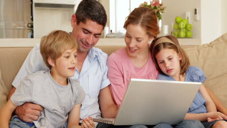 Glückliche-Junge-Familie-Sitzt-Auf-Dem-Sofa-Und-Benutzt-Gemeinsam-Einen-Laptop