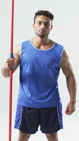 Vertical-video:-Biracial-male-athlete-holding-red-pole,-white-background