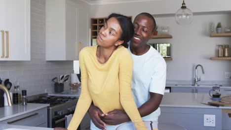 Una-Pareja-Diversa-Comparte-Un-Tierno-Momento-En-La-Cocina,-Abrazándose