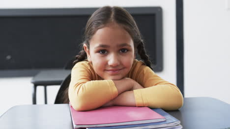 In-a-school-setting,-a-young-Caucasian-girl-sits-at-her-desk