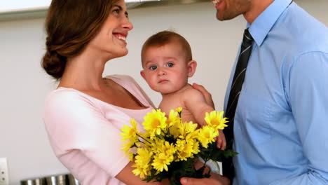 Mother-holding-baby-with-father-holding-yellow-flowers