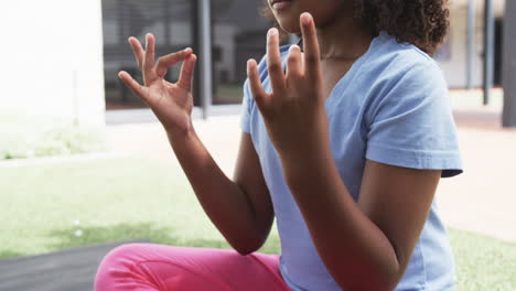 Biracial-girl-meditates-outdoors,-fingers-touching-in-a-mudra-pose