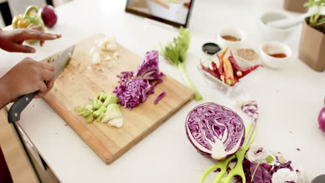 African-American-woman-is-chopping-vegetables-on-a-wooden-cutting-board-at-home