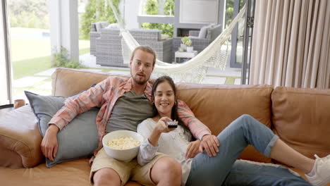 A-young-biracial-couple-relaxes-on-sofa,-cozy-home-interior