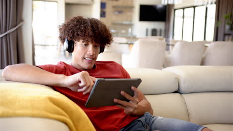 Un-Joven-Birracial-Está-Usando-Su-Tableta-En-Un-Sofá-En-Casa