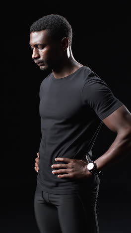 Vertical-video:-African-American-male-athlete-posing,-black-background