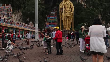 Tourists-Crowd-amid-Pigeons-Flock-taking-pictures-at-Statue-of-Batu-Caves-Temple,-Kuala-Lumpur