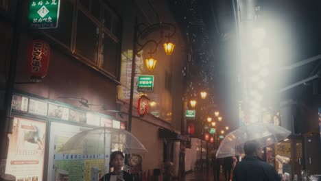 People-With-Umbrellas-On-Wet-Rainy-City-During-Nighttime-In-Osaka,-Japan