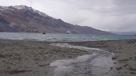 Agua-De-Corriente-Glacial-Que-Fluye-Hacia-El-Frío-Mar-ártico-Con-Crucero-Y-Costa-De-Groenlandia-En-Segundo-Plano