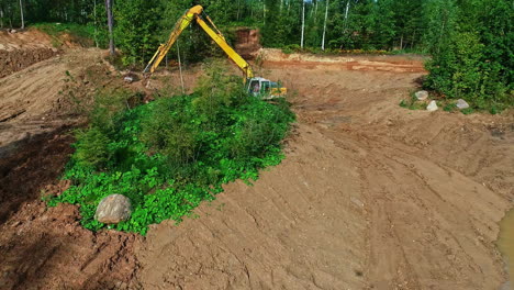 Máquina-Excavadora-Trabajando-En-Un-Bosque-De-Pinos-Verdes-Quitando-Tierra,-Revelando-Toma-Aérea