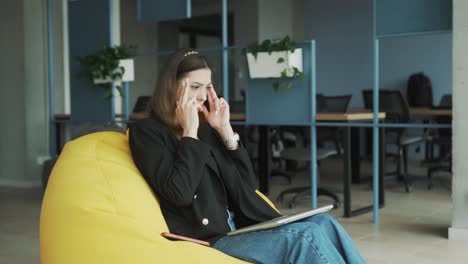 Hübsche,-Müde-Frau-In-Business-Kleidung-Sitzt-Auf-Einem-Hocker,-Schließt-Ihren-Laptop-Und-Beginnt,-Ihre-Schläfen-Aufgrund-Einer-Migräne,-Kopfschmerzen-Und-Erschöpfung-Zu-Massieren