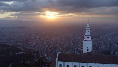 Toma-De-Drone-De-La-Iglesia-De-Monserrate-Con-Vistas-A-La-Ciudad-De-Bogotá,-Colombia-Al-Atardecer.