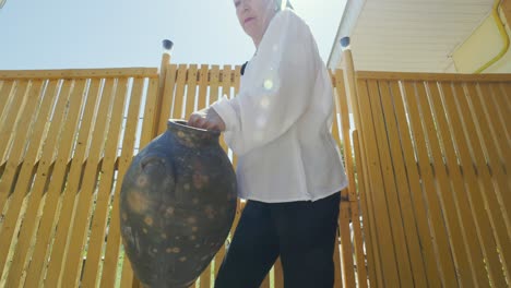 Mujer-Rumana-Saliendo-Con-Una-Jarra-De-Cerámica-Tradicional-Para-Buscar-Agua-Del-Pozo.