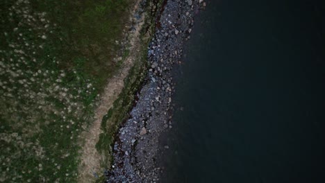 Drone-shot-above-rocky-coastline-with-dark-waters-of-Barents-sea