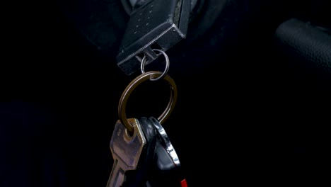 Slow-motion-close-up-of-hand-reaching-for-swinging-car-keys-in-ignition-engine-start-vehicle-safety-security-transport-starting-driving-keyring-sensor