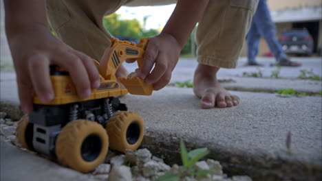 Cámara-Lenta-De-Un-Joven-Latino-Mexicano-Irreconocible-Jugando-Con-Una-Excavadora-De-Juguete-En-El-Frente-De-Su-Casa-En-México