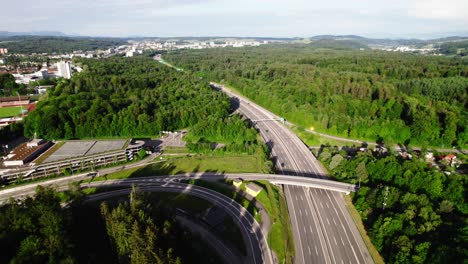 Aerial-view-of-a-6-lane-highway-through-lush-forests-in-Switzerland