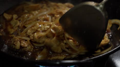 Cooking-seasoned-onions-and-chicken-in-a-Chinese-metal-wok-over-high-heat