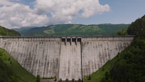 Dam-and-water-reservoir,-ascending-aerial-view,-sunny-day