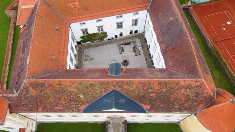 Drone-Shot-of-Slovenska-Bistrica-Castle-located-in-northeastern-Slovenia-with-Tennis-Counts-and-Greenery-Surrounding-the-Castle