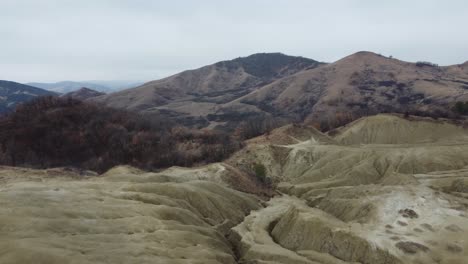 Aerial-perspective-of-the-volcanic-landscape-of-the-mountains-of-Romania-with-its-mud-volcanoes,-dry-land-with-cracks,-with-some-isolated-houses-and-villages