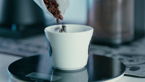 Putting-Coffee-Beans-into-a-white-Cup-to-be-measured-on-the-scale