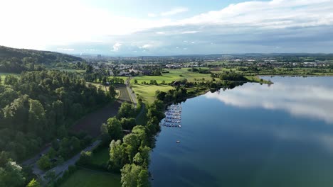 Vista-Aérea-Del-Reflejo-Del-Cielo-Sobre-El-Lago-Greifensee-Y-El-Paisaje-Verde,-Suiza