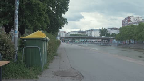 Los-Ciclistas-Pasan-Por-Contenedores-De-Reciclaje-A-Lo-Largo-Del-Canal-De-Viena.