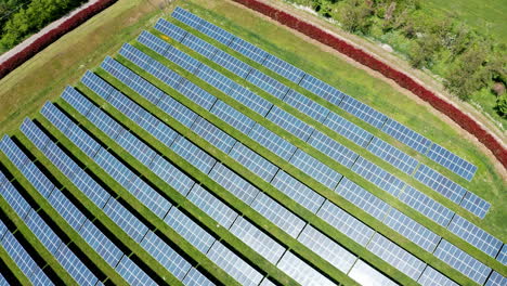 Una-Gran-Granja-Solar-Con-Hileras-De-Paneles-Solares-Sobre-Hierba-Verde,-Vista-Aérea